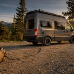 Portable inverter generator safely positioned away from a camper van at a mountain campsite